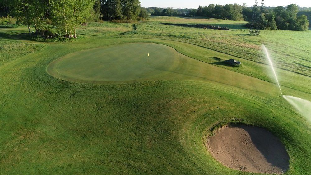 Vattenspridare som vattnar gräset på golfbanan.