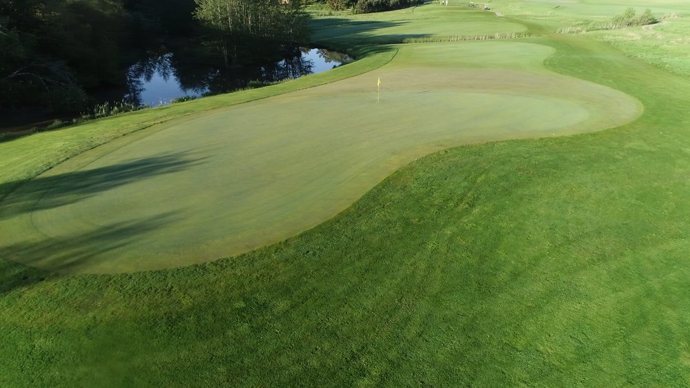 Golfbana med en liten sjö.