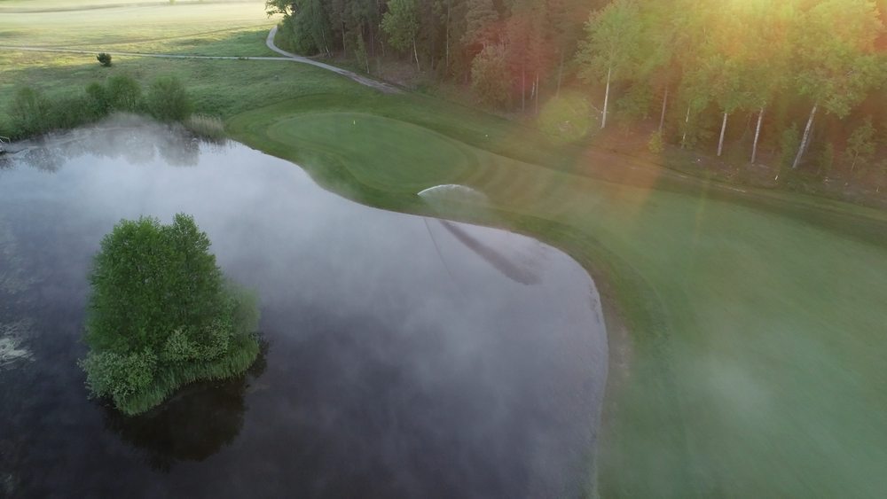 Vattenspridare som vattnar gräset på golfbanan.