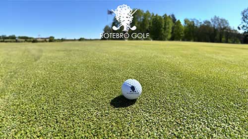 Golfbana täckt i dimma i en solnedgång.